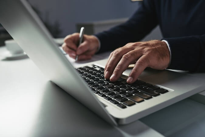 Mãos masculinas digitando em notebook.