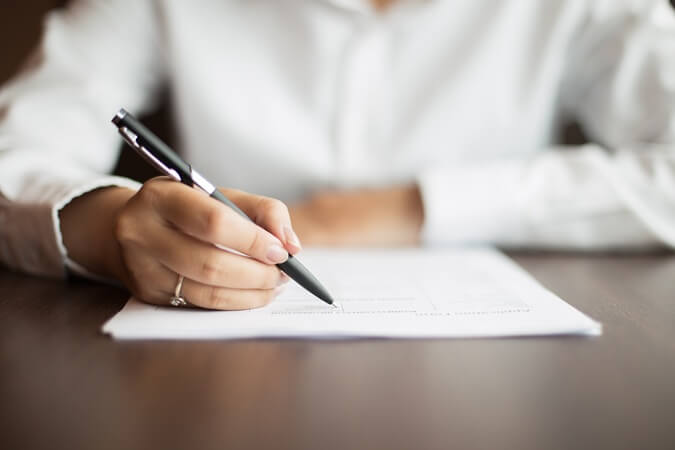 Mãos femininas assinando documento